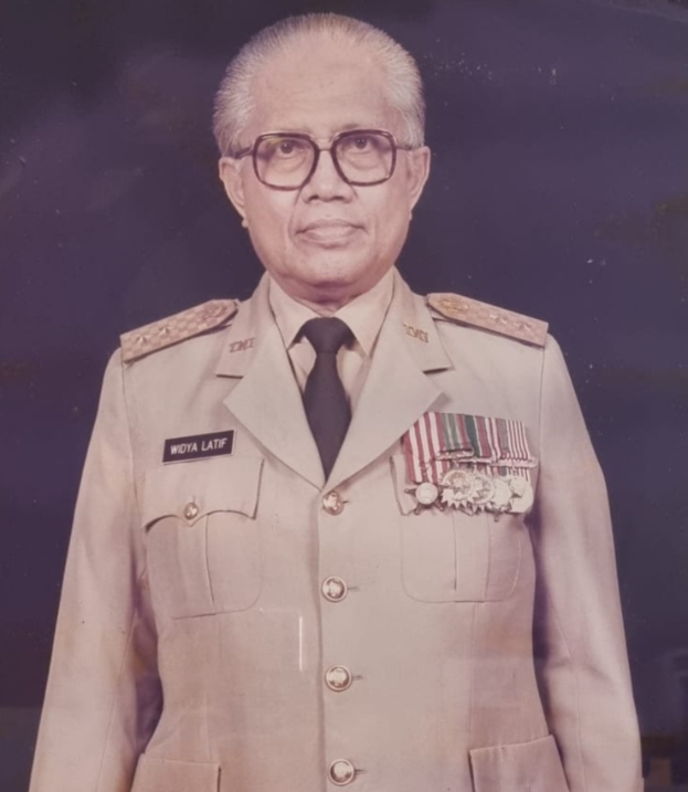 Ein altes Foto eines Mannes in Uniform mit Blazer, Krawatte und Brille sowie Abzeichen auf der Brust.