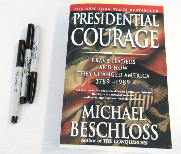 Eine weiße Oberfläche mit einem Buch namens "Presidential Courage: Brave Leaders and How They Changed America 1789-1989" von Michael Beschloss und zwei Stiften.
