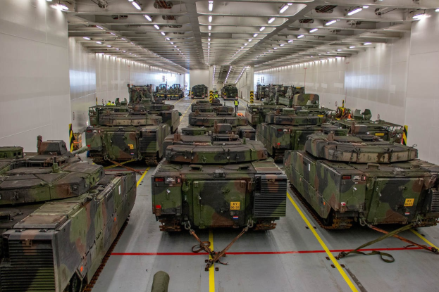 Ein grosser Militaraustellungsraum mit Reihen von Militarafahrzeugen, Wanden an beiden Seiten und Deckenleuchten.