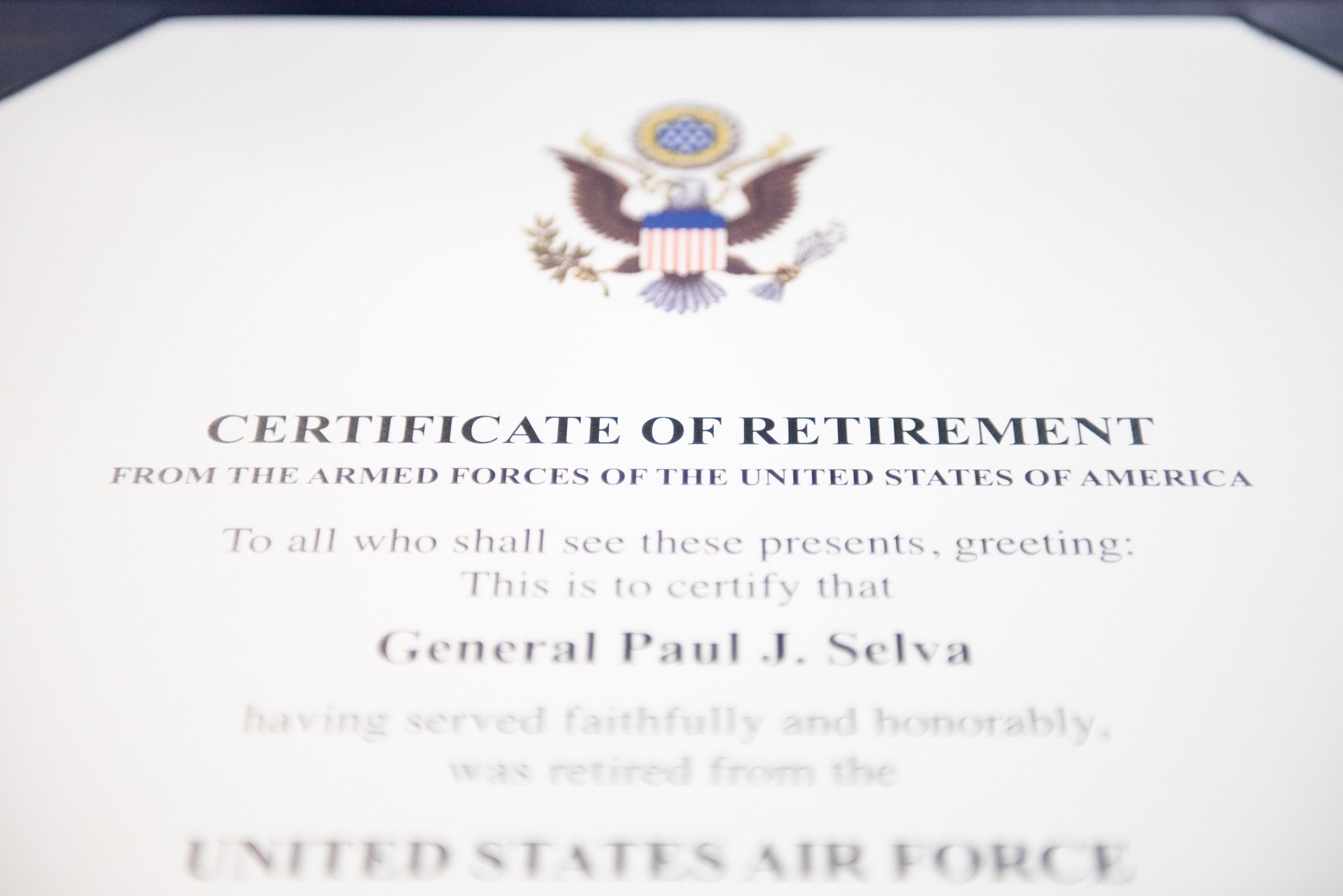 Rahmenurkunde für den Ruhestand der United States Air Force mit blauem Rand, die ein zentrales Schild-Logo mit einem Stern, einem Lorbeerkranz und einer schwarzen Schriftzeile "Ruhestand" zeigt.