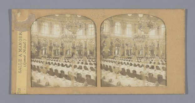 Ein altes Foto eines prächtigen Hotel-Speisesaals mit Kronleuchtern, langen Tischen und Stühlen, auf dem links ein Schild mit der Aufschrift "Sale à Manger, Grand Hotel" zu sehen ist.