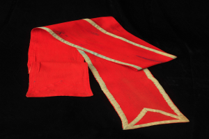 Ein roter Umhang mit goldenem Saum auf schwarzem Hintergrund, der eine tiefe rote Farbe und goldene Ränder für einen luxuriösen und eleganten Look bietet.