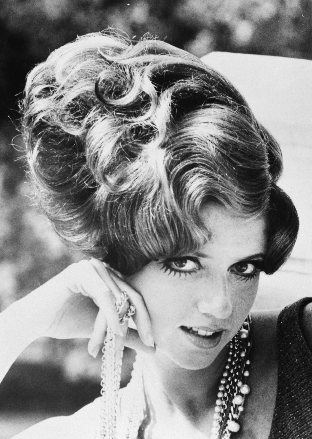 Schwarzes und weißes Foto von Prinzessin Diana in einem Kleid und Schmuck mit unscharfem Hintergrund.