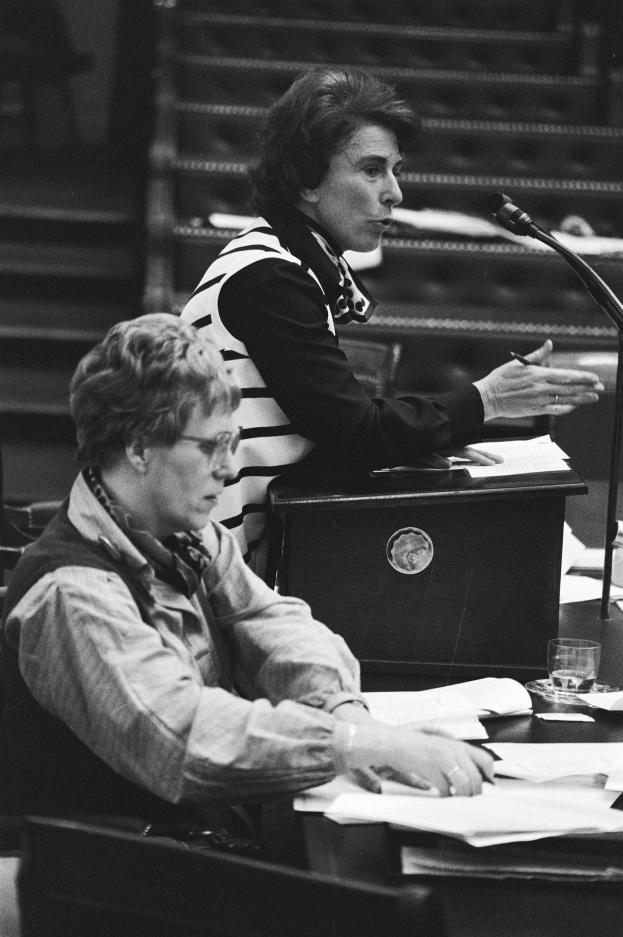 Frau sitzt an einem Tisch im Europäischen Parlament in Straßburg im Mai 1981, hält einen Stift mit Papieren, ein Glas Wasser und andere Gegenstände auf dem Tisch, Treppe im Hintergrund, Schwarz-Weiß-Fotografie.