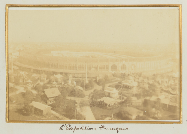 Altes Schwarz-Weiß-Foto eines Stadions in einer städtischen Umgebung mit umgebenen Gebäuden, Bäumen und Strommasten; unten sichtbarer Text.