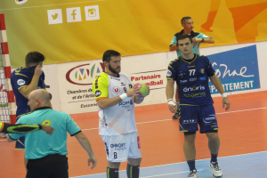 Eine Gruppe von Männern steht auf einem Futsal-Platz, einer hält den Ball, links ein Tor und im Hintergrund Banner.