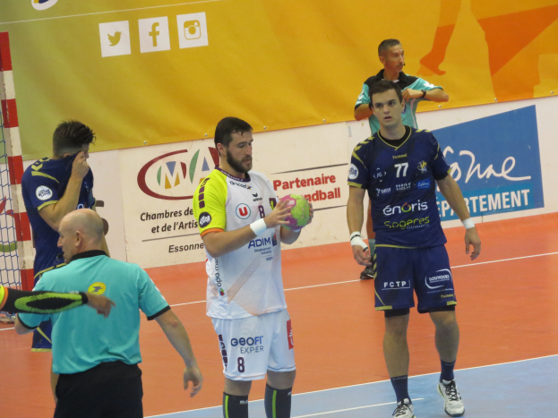 Eine Gruppe von Männern steht auf einem Futsal-Platz, einer hält den Ball, links ein Tor und im Hintergrund Banner.
