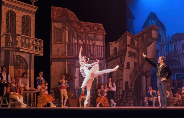 Zwei Tänzer performen auf der Bühne im Royal Opera House in London, mit einem sitzenden und stehenden Publikum im Hintergrund.