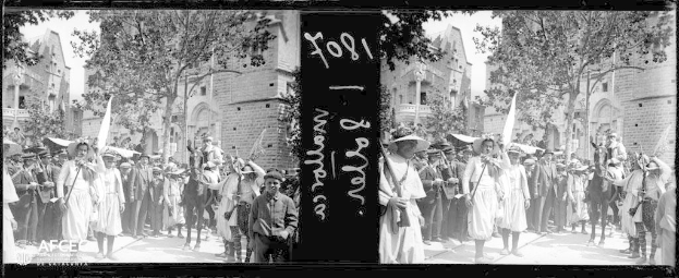 Eine Gruppe von Menschen steht vor einem Gebäude, einige halten Fahnen und tragen Hüte, während sie an einer Protestdemo in New York City teilnehmen, mit Bäumen und Gebäuden im Hintergrund in Schwarz-Weiß.
