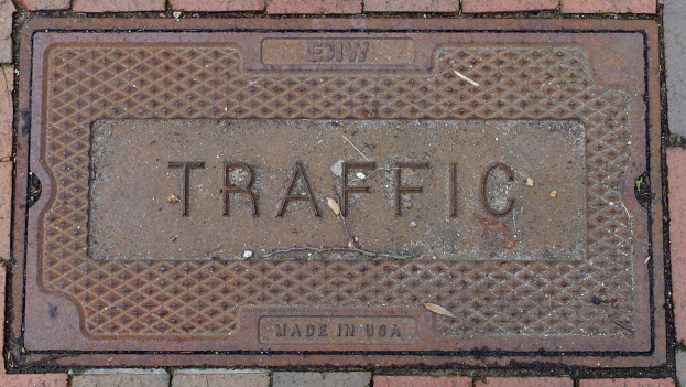 Ziegelweg mit einer Metallschachtdüse, die mit "Verkehr" beschriftet ist