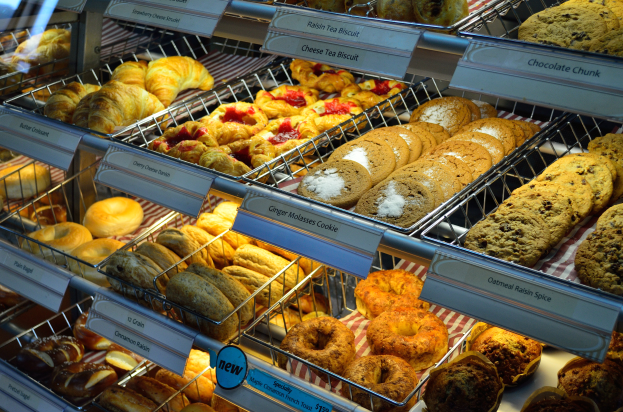 Ein Bäckereischaufenster voller verschiedener Kuchen, Torten, Plätzchen und anderer Backwaren, mit Schildern, die die Art der Backwaren angeben.