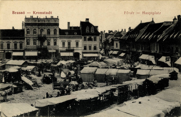 Schwarzes und weißes Foto eines belebten Marktes in Kronstadt, Deutschland mit Menschen, Zelten und Gebäuden im Hintergrund.