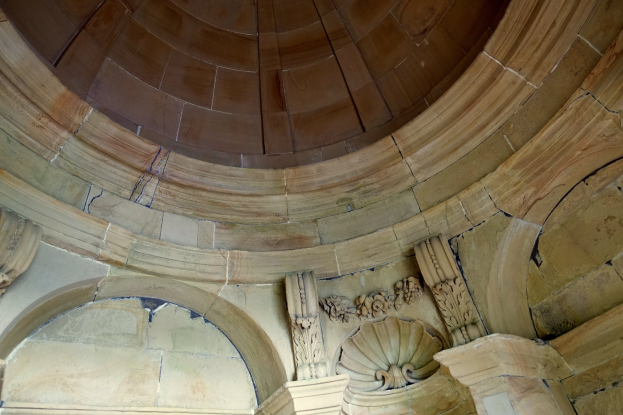 Altes Steingebäude mit Kuppeldecke und detaillierten Wandverzierungen.