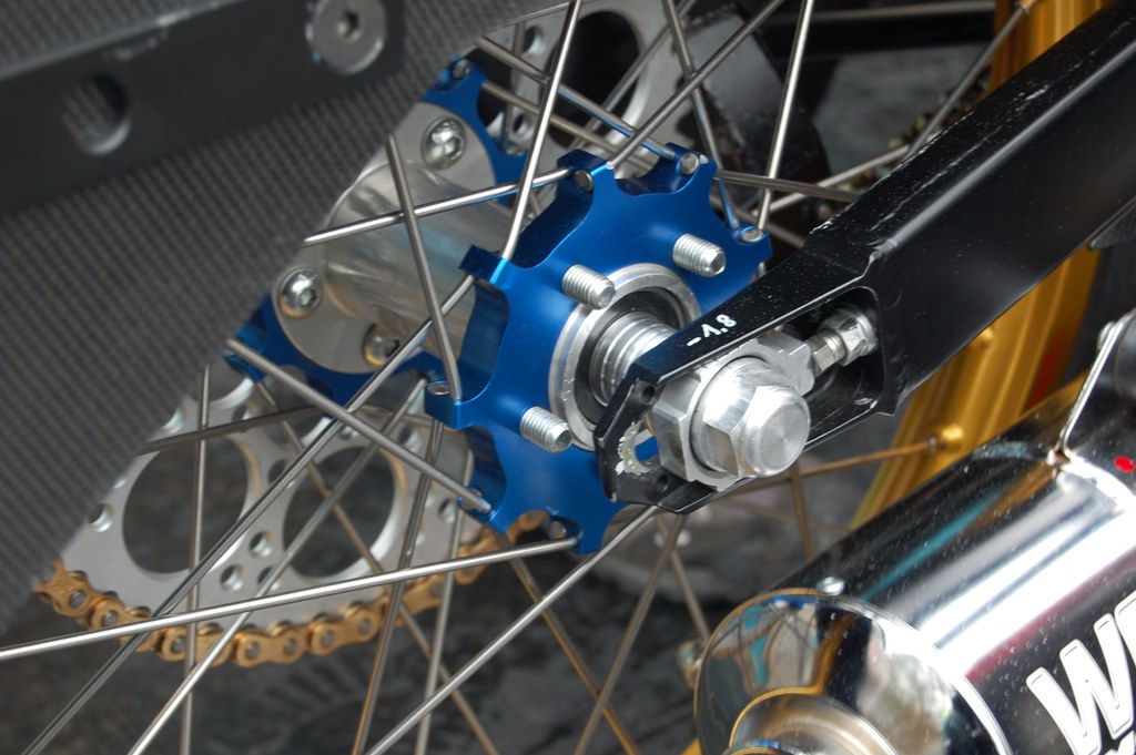 Ein Motorradrad und ein Endschalldämpfer sind im Bild zu sehen.