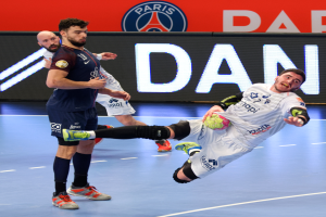 Eine Gruppe von Männern, die Handball auf einem Platz spielen, einer hält den Ball, mit einem Hintergrundschild von Paris Saint-Germain Futsal.